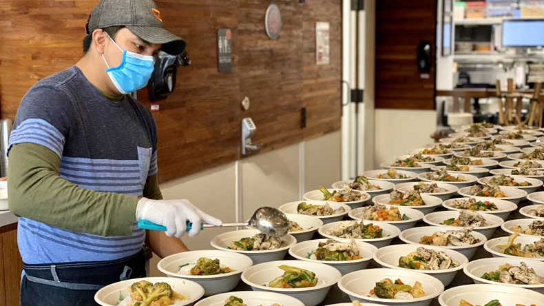 A cook at Immigrant Food fills grain bowls Elizabeth Sanjuan Photography